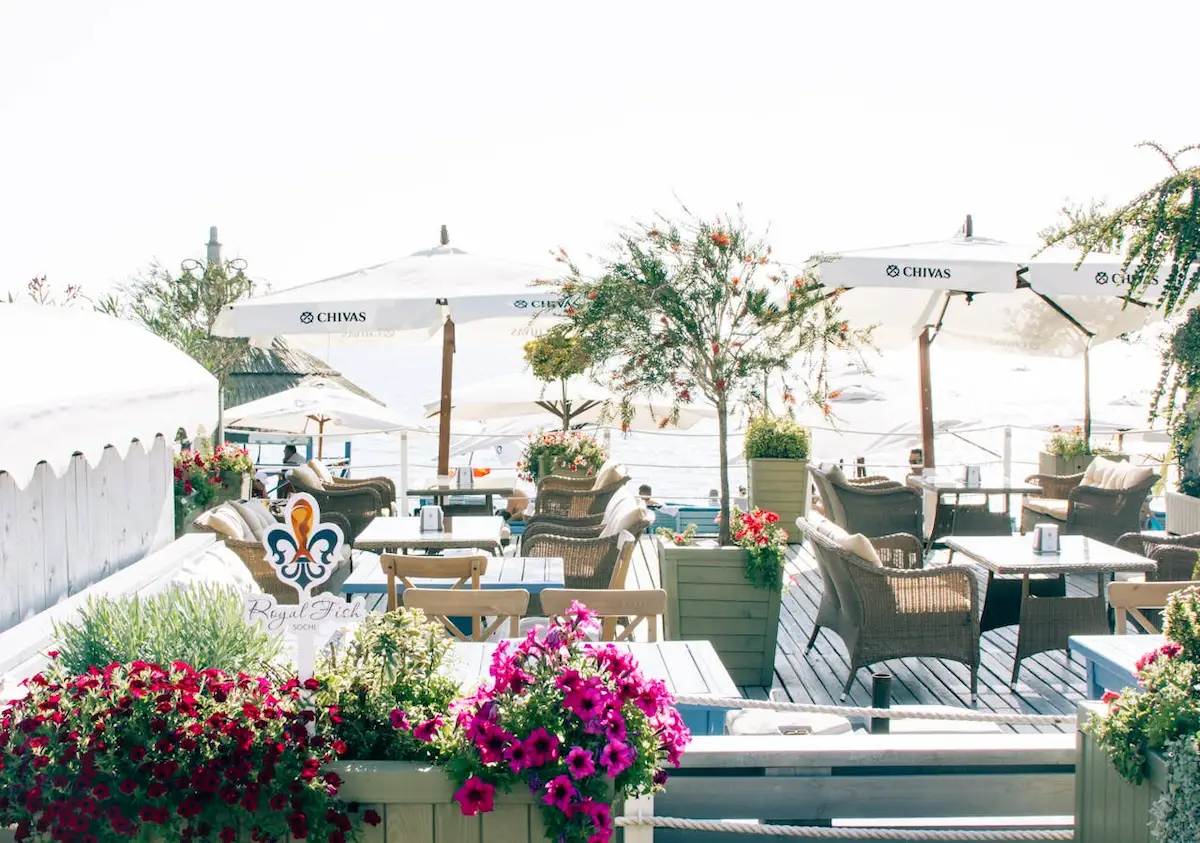 outdoor seaside restaurant terrace with white umbrellas and colorful flowers