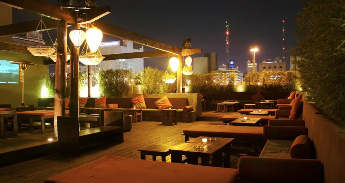 Rooftop bar in Malaga, Spain at night with cozy lounge seating, warm lantern lighting and city skyline views.