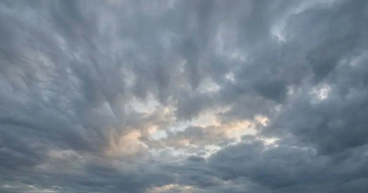Overcast November sky above Malaga, showing typical weather in November with soft, realistic cloud formations and subtle light breaking through, creating a moody and atmospheric scene.