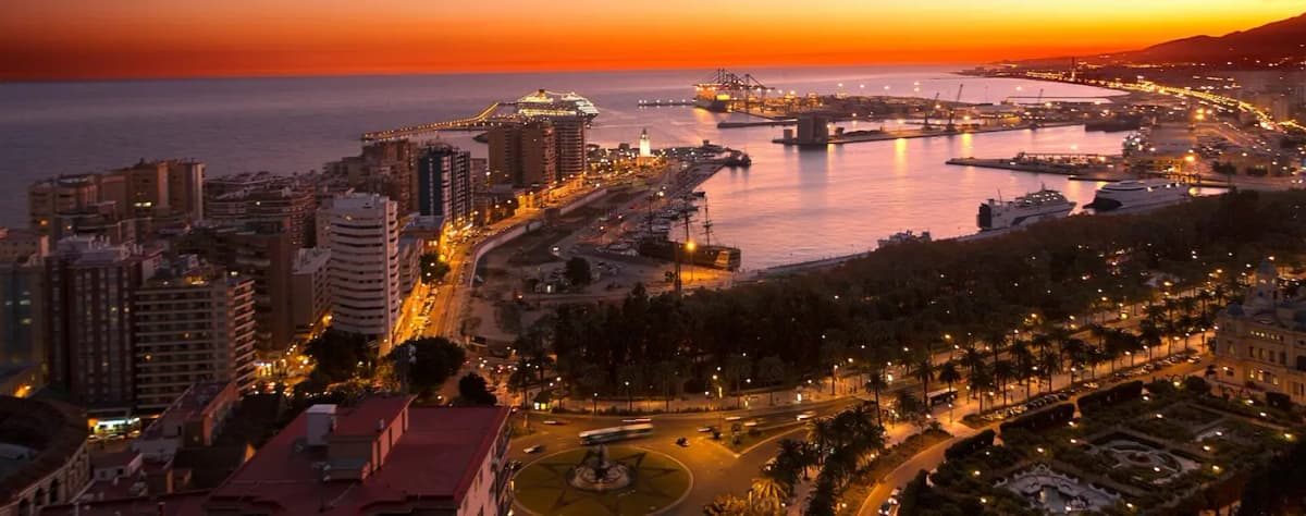A scenic view of Malaga's seafront with the Alcazaba fortress above and the Mediterranean sea in the foreground on a sunny day.