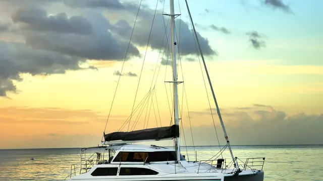 Sailing catamaran anchored off Puerto Banús at sunset