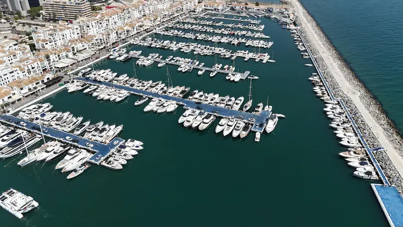 Luxury yachts docked in Puerto Banus marina with white Andalusian buildings and La Concha mountain in the background, Marbella, Spain.